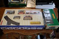 Top-down view of original LEMAX train set box showing the locomotive, passenger, cargo cars, and track pieces inside.