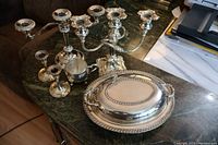 Full lot view showing 2 candelabra, 2 small candlesticks, creamer, oval serving dish with glass liner on top