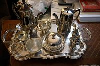 Full view of the tea set arranged on the large silver plate tray including teapot, coffee pot, cream and sugar container, covered butter dish, salt and pepper shakers, and waste bowl.