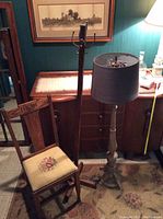 View of coat rack, floor lamp, antique chair with petit point floral seat, and room background