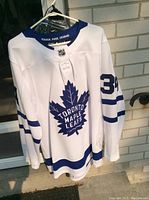Front of white jersey showing Toronto Maple Leafs crest and sleeve number 34