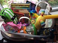 Large plastic container showing a mix of children's toys and books from various angles, including colorful toys and headphones.