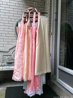 Hangers holding six vintage silk slips in various pastel shades with lace trim.