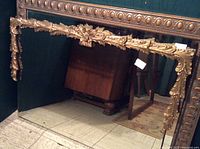 Full view of the large gold filigree antique mirror showing the detailed crown moulding and beveled glass edge.