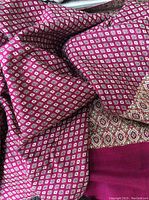 Close-up image showing rose and tan pashmina shawl with geometric patterns and solid rose border.