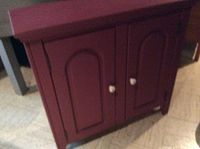 Front angled view of small painted wooden hutch showing two doors and white knobs