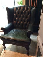 Full front view of the hunter green leather wingback chair