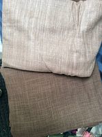 Two folded pieces of brown raw silk fabric, one darker and one lighter brown, stacked on each other to show the texture and color difference.