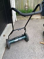 Side view of manual push reel lawn mower showing padded handlebar and wheels