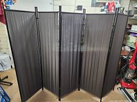 Front view of the 5 panel room divider showing its full width and black sheer fabric over metal frames.