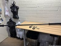 Full length view of the 7-foot black Weider weight lifting bar resting on a table with clips beside it.