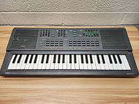 Front view of Yamaha Portasound keyboard showing full 49-key layout, control sliders, buttons, and stereo speakers.