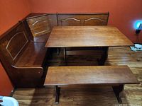 Wide view of breakfast nook set showing table, corner benches with backrests against wall, and bench in front.