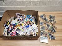 Cardboard box containing a large quantity of loose sports trading cards.