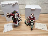 Two Lenox Santa Claus figurines on display with original Lenox boxes and Certificates of Authenticity shown next to each figure.