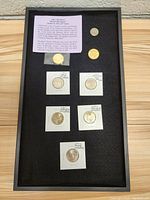 Display case with seven gold plated coins and informational card on Missouri Quarter