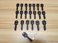 Top view of 20 black key shaped folding cutters, one with blade open to show folding utility cutter.