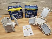 Two boxes and two Bright Living multi-directional LED lights with three adjustable light panels each spread on a wooden surface.