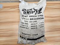 Photo showing sealed white fabric bag labeled Quik Grip Light Truck Chain stock QG3229CAM with tire sizes and quantity information.