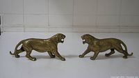 Pair of bronze cougar sculptures facing each other on a white surface