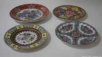Four Chinese hand painted decorative plates arranged in a group, showing varied colorful floral and traditional designs.
