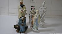 Front view of all five Chinese figurines showing variety in posture, attire, and style