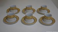 Six porcelain cups with matching saucers arranged in a group, showing all sets.