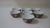Seven Jingdezhen porcelain rice bowls arranged in two rows with white tiled background.