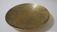 Top view of antique bronze plate showing full dragon design on interior surface.