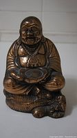 Front view of bronze Buddha figurine showing detailed facial features, necklace, and bowl held in hands.
