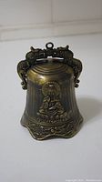 Front view of bronze bell with detailed Buddha figure and dragon handle.