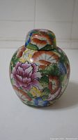 Front view of the floral porcelain jar showing colorful flowers painted on the body.