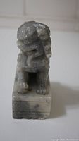 Front view of gray jade lion figurine showing detailed face and mane on rectangular base.