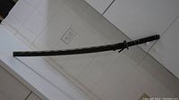 Full view of samurai sword sheathed in a black textured scabbard