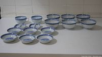 Front view of all blue and white porcelain bowls and cups arranged on a white surface, showing multiple sizes and shapes of dinnerware.