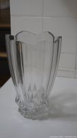 Full view of clear glass vase showing scalloped top edge and geometric cut design.
