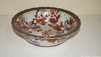 Wide-angle photo showing the entire bowl with its brown scalloped rim and multicolored floral interior design.