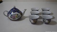 Full view of the tea set showing one teapot and five small tea cups arranged in an arc