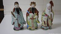 Front view of all three Fu Lu Shou porcelain statues side by side showing their colors and size comparison