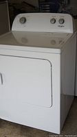 White Whirlpool electric clothes dryer in a storage space showing front and side view.