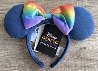 Disney Pride Collection denim Minnie Mouse style ears featuring a rainbow satin bow on a denim covered headband, new with attached tags.