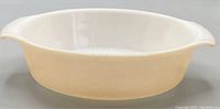Side view of oval iridescent peach baking dish with side handles.