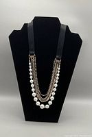 Front view of the Lane Bryant gold tone faux pearl and black strap layered necklace displayed on a black bust form.