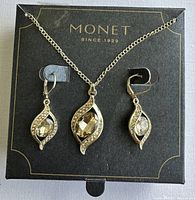 Photo showing Monet brand gold tone necklace and earring set with crystal embellishments on black Monet box.