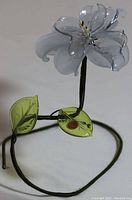 Full view of Murano glass flower with wire stem and green leaf on base.
