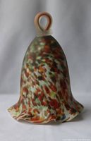 Front view of hand blown multicolor glass bell with ruffled bottom edge and loop handle.