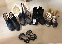Overview showing four pairs of winter boots and a pair of detachable ice grips on the floor