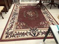 Full view of machine made area rug with floral medallion and cream border with floral motifs showing overall pattern and condition