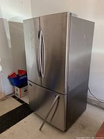 Front and side view of stainless steel French door top and bottom freezer drawer with detached handle on floor