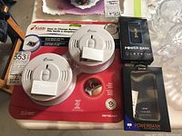 Two Kidde smoke alarms in red packaging with battery packets and two FLIR power banks boxed